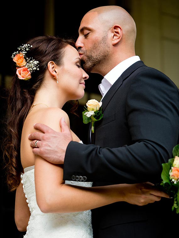 Groom kissing the forehead of his bride tenderly