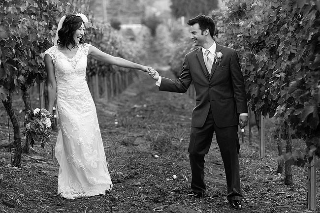 Bride and groom next to grapevine at a vinery in Temecula